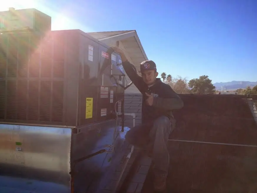 HVAC technician performing Heat Pump Repair on a rooftop unit in Huntingburg